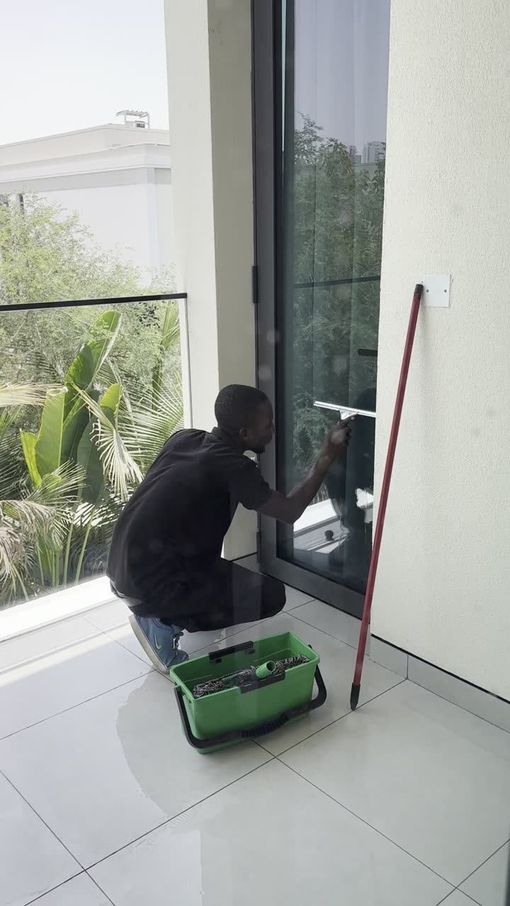 Glastuer wird mit Abzieher gereinigt, Pool im Hintergrund